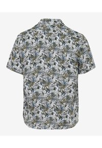 Camisa de manga corta en una tela ligera, con un patrón de follaje verde y azul sobre un fondo blanco, con cuello tipo polo y dobladillo curvo.