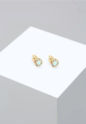Boucles d'oreilles clous en ton or, présentant une pierre opalescente entourée d'un halo de cristaux transparents. Design rond, avec une finition polie.