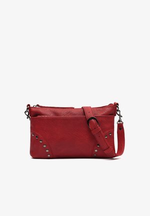 Bolso bandolera de cuero rojo con correa ajustable, bolsillo frontal con cremallera y detalles de tachuelas metálicas en las esquinas.