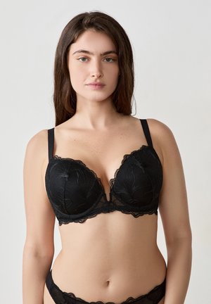 Reggiseno in pizzo nero con scollatura profonda, caratterizzato da bordi ondulati e ricami floreali. Include spalline regolabili e supporto con ferretto.