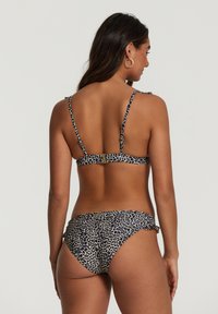 Bikini z leopardjim motivom, ki ima tanke nastavljive naramnice, zaponko in nagubane detajle na hlačkah, izdelan iz gladkega blaga.