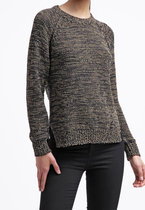 Stickad tröja i ett prickigt mönster av svart och beige. Har en rundad halsringning och ribbade ärmslut, med en avslappnad, något lös passform.