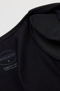 Czarny element bielizny wykonany z gładkiej tkaniny, z miękkimi krawędziami, z metką pielęgnacyjną wskazującą rozmiar S oraz szczegółami wzoru.