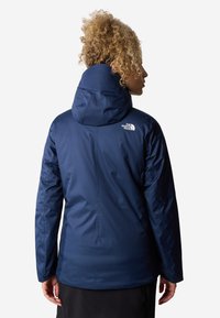 Tamsiai mėlynas vandeniui atsparus džemperis su gobtuvu, su užtrauktuku, elastinėmis rankovėmis ir "The North Face" logotipu viršutinėje nugaros dalyje.
