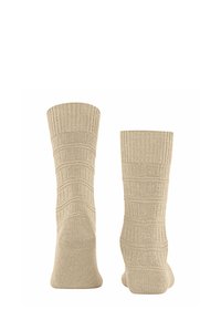 Calzini beige con texture e design a coste, caratterizzati da linee orizzontali e verticali alternate, con punta e risvolto arrotondati.