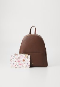 Zaino in finta pelle marrone con forma rotonda e hardware dorato, abbinato a un portacarte con motivo floreale nei colori tenui.