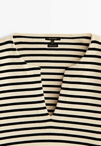 Haut en maille rayé horizontal noir et blanc avec un encolure en V entaillée, fabriqué en Turquie, taille moyenne.