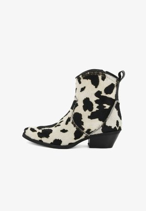Stivali cowboy alla caviglia con un motivo in pelle bovina bianca e nera, punta affusolata, tacco basso a blocco e una linguetta sul retro per indossarli facilmente.