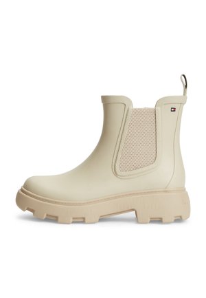 Beiger knöchelhoher Gummistiefel mit grober Sohle, elastischem Seitenteil, Zuglasche an der Ferse und kleinem rechteckigem Logo nahe dem oberen Rand.