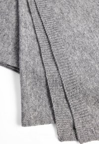 Tissu en tricot gris, mettant en valeur une texture douce avec un motif chiné subtil. Présente des accents côtelés le long des bords.