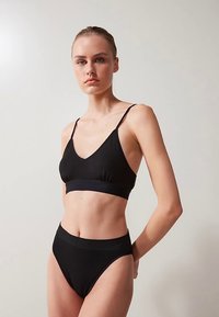 Svart bralette och högmidjad trosa i set. Mjukt, stretchigt tyg med slät textur. Minimalistisk design med smala band och subtil ribbning.