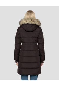 Zwarte gewatteerde jas met capuchon en nepbontkraag, met een doorgestikt ontwerp, lange mouwen en een getailleerde taille. Achteraanzicht, model draagt lichte jeans.