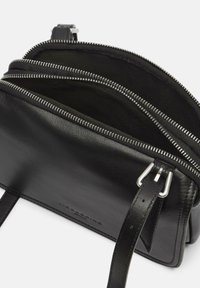 Borsa a tracolla in pelle nera con cerniere argentate, caratterizzata da più scomparti e da un design strutturato. Spallacci regolabili e superficie liscia.