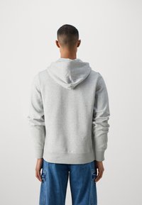 Gray hooded sweatshirt with a soft texture, featuring a kangaroo pocket and ribbed cuffs, paired with loose blue denim pants.