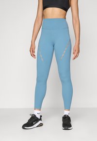 Világoskék, magas derekú sportleggings, vágott részletekkel az oldalain. Nyújtható, nedvességelvezető anyagból készült.