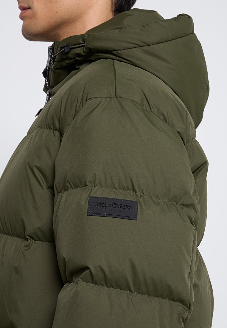 Grüne Pufferjacke mit abnehmbarer Kapuze, gestepptem Design und einem schwarzen Logo-Patch auf der linken Schulter. Glattes, strukturiertes Material.