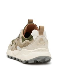 Laufschuh mit einem strukturierten beigefarbenen und olivgrünen Obermaterial, weißen Akzenten und einer klobigen cremefarbenen Laufsohle mit grauen Traktionsnoppen und einer Schlaufe an der Ferse.