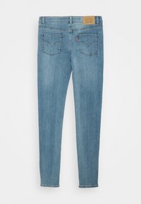 Jeans ajustados en denim azul claro con una textura suave, diseño de cinco bolsillos, un lavado ligeramente desvanecido y una etiqueta de cuero con marca en la cintura.