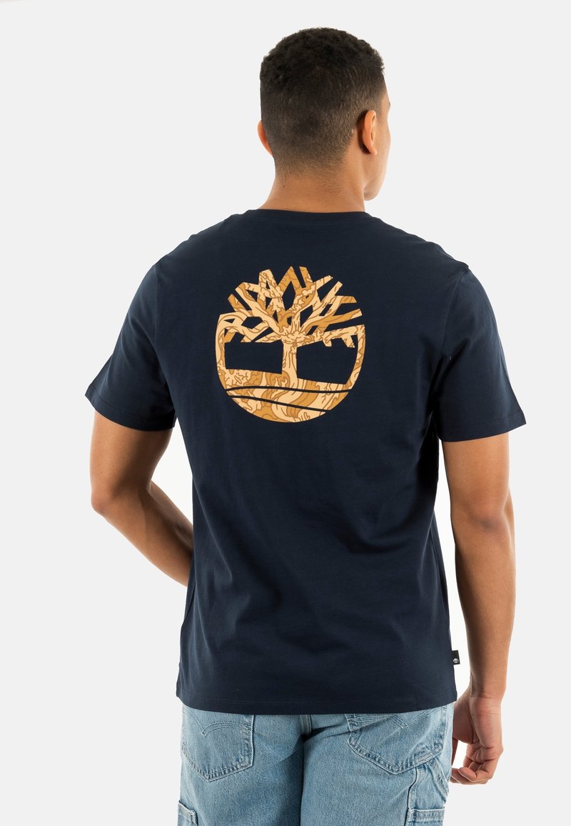 T-shirt en coton marine avec un grand logo d'arbre marron clair et un design circulaire au dos. Manches courtes et col rond.