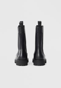 Black leather ankle boots with elastic side panels, pull tabs, and thick rubber soles. Features a smooth texture and a sleek, minimalist design.