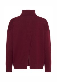 Pull col roulé bordeaux avec une coupe décontractée, poignets côtelés et détail fendu au dos. Texture douce, manches longues et épaules tombantes.