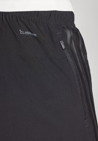 Schwarze Sportshorts aus glattem Material mit einem elastischen Bund und einer seitlichen Tasche mit Reißverschluss. Mit CLIMACOOL-Logo am Bund.