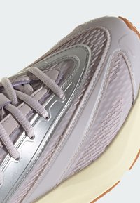 Sportske tenisice u svijetlo lavandi i srebrnoj boji, s teksturiranim mrežastim gornjištem, sintetičkim detaljima i gumenim potplatom. Suptilne linije dizajna.