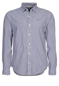 Knappad skjorta med långa ärmar, blå och vita vertikala ränder. Har en klassisk krage, framknäppning och liten logotyp på bröstet.