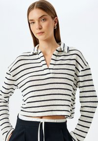 Gestreepte pullover in crème met marineblauwe horizontale strepen, textuur gebreid, diepe V-hals, cropped ontwerp, losse pasvorm, lange mouwen.