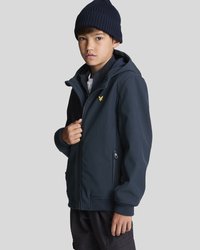 Giacca a zip con cappuccio di colore blu navy, realizzata in un tessuto morbido, con un logo sul petto sinistro e tasche laterali con zip. Indossata con un berretto in maglia scura.