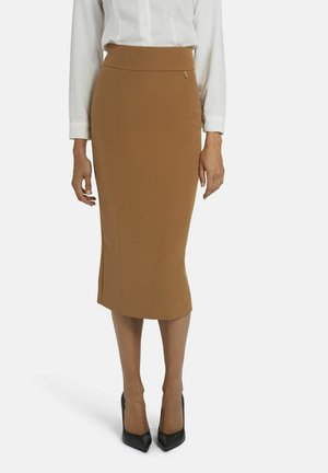 Jupe crayon marron en tissu extensible, avec une taille haute et une coupe ajustée, associée à des escarpins noirs à bout pointu.