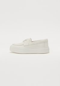 Hvite lær slip-on sko med rund tå, minimal søm, og tykk hvit gummisåle. Har sideakenter for snøring.