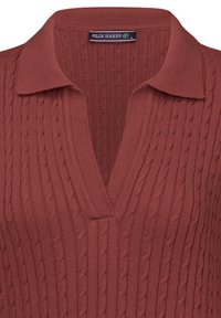 Sweter polo w kolorze rdzy, z dekoltem w serek, z teksturowanym wzorem w warkocze i ściągaczem przy kołnierzu. Etykieta marki widoczna wewnątrz dekoltu.