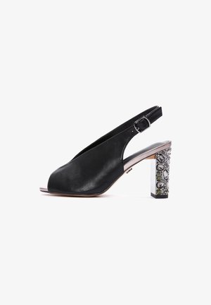 Zapato de tacón tipo slingback con abertura en la punta, hecho de cuero negro, con correa ajustable con hebilla y tacón grueso adornado con diversas gemas brillantes.