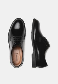 Zwarte leren dresschoenen met een gladde afwerking, vetersluiting, ronde neus en een contrasterende zool. Het interieur heeft een gegraveerde inlegzool.