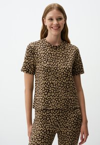 Luipaardprint top en bijpassende broek in bruin en beige. Korte mouwen, ronde halslijn, ontspannen pasvorm, zachte stofstructuur en opvallend patroon.