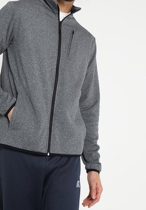 Grå zip-up fleecejacka med hög krage, svart dragkedja och bröstficka. Har en texturerad yta och ribbade muddar.
