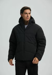 Giacca a vento nera con cappuccio, caratterizzata da un design trapuntato, maniche lunghe e tasche anteriori con zip. Texture liscia e materiale leggero.