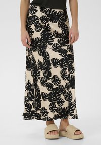 Beige maxi szoknya fekete trópusi levélmintával, puha anyagból készült. Légies megjelenéssel és bokáig érő szegéllyel rendelkezik.