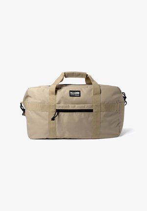 Sac de sport rectangulaire beige avec poche zippée à l'avant, double poignées solides avec prise rembourrée, et étiquette de la marque Palladium centrée au-dessus de la poche.