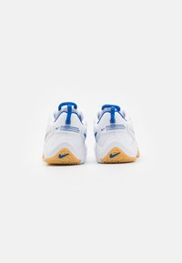 White athletic shoes with blue accents, rounded heel, textured rubber outsole, and stitched details, featuring branding on the back.
