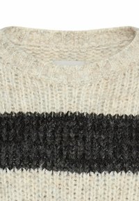Chunky gebreid sweater met een brede zwarte horizontale streep over crèmekleurige stof en een ronde halslijn.