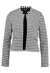 Giacca con motivo houndstooth in bianco e nero, dal taglio cropped, con scollatura tonda e maniche lunghe. Apertura frontale senza chiusure.