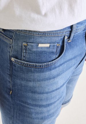 Pantalones vaqueros de denim azul con un corte clásico, que presentan un bolsillo trasero y una etiqueta que dice "ANTONY MORATO". La costura es de un color contrastante.