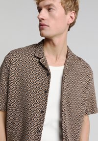 Korte mouw shirt met een ruitpatroon in bruin en zwart, gemaakt van gewoven stof, met een knoopsluiting aan de voorkant en een relaxte kraag.
