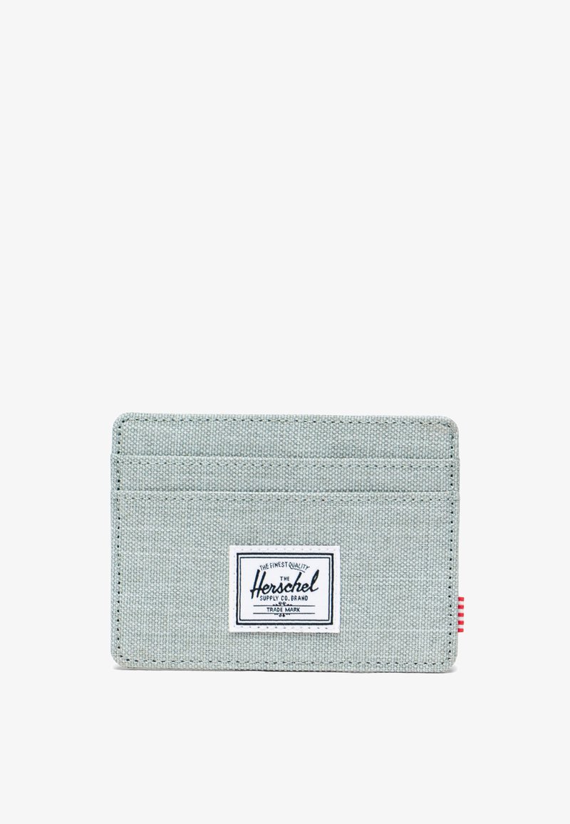 Jasnoszary portfel na karty wykonany z tkaniny, z czterema przegródkami na karty i białą naszywką z logo. Zawiera czerwono-biały, paskowany akcent po boku.