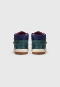 Høye sneakers i mørk teal semsket skinn med en marineblå stoffkrage. Har en borrelåsrem og en teksturert gummisåle.