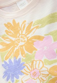 Ljusrosa bomulls-T-shirt med ett blommönster i gult, lila och rosa med gröna detaljer. Rundhalsad design och mjuk textur.