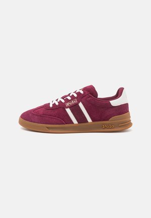 Bordowe zamszowe sneakersy z białymi sznurówkami, białymi paskami i brązową gumową podeszwą, z marką "Polo" na boku i pięcie.