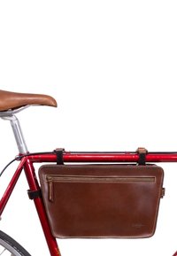Leren zadeltas in donkerbruin, voorzien van een ritszak, bevestigd aan een rode fietsframe met zwarte riemen en stiksels.